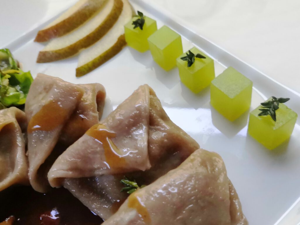 Steinpilztortellini angerichtet mit Sauce und Birnen-Thymiangeleewürfeln