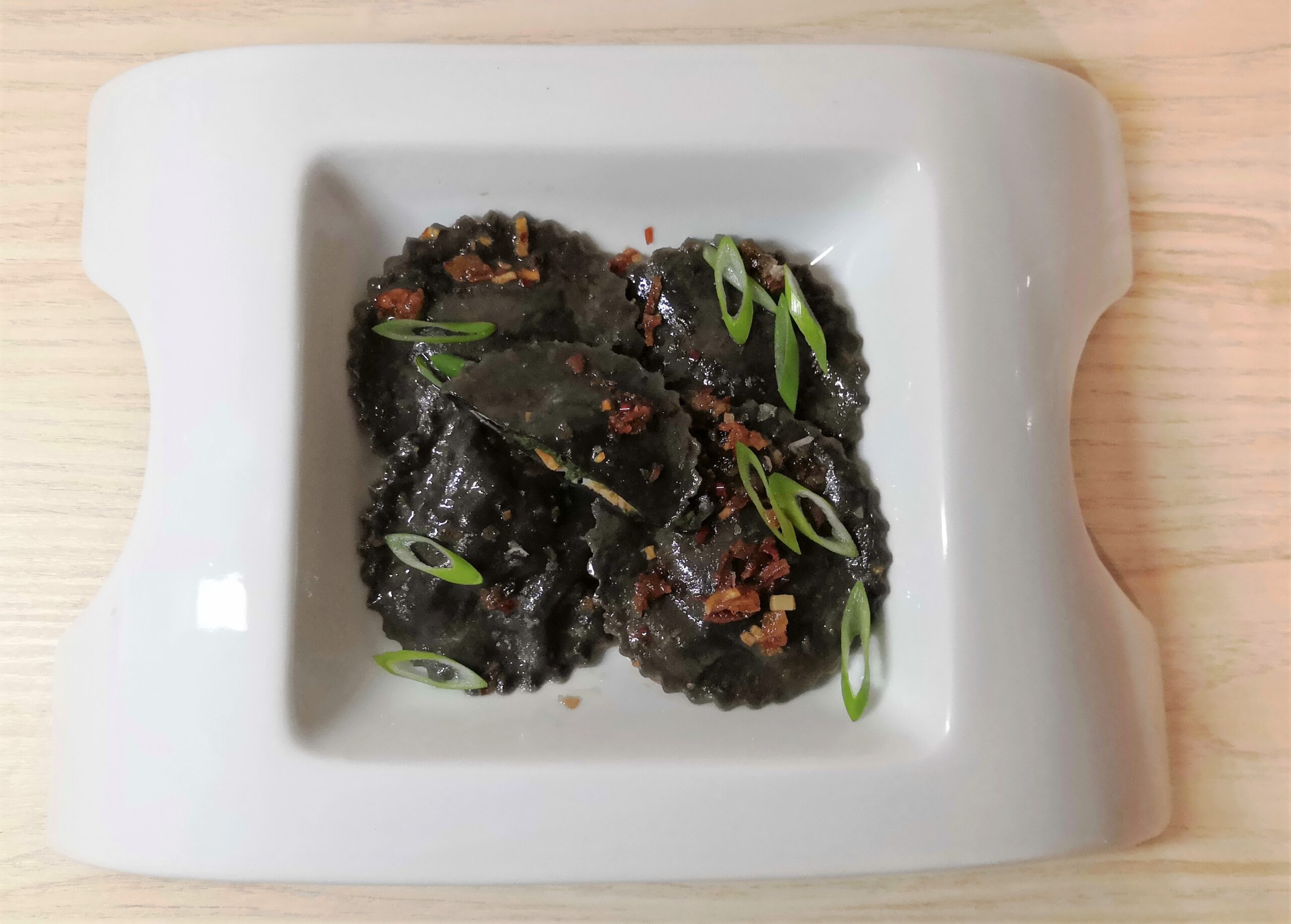 Schwarze Ravioli mit Lachsforelle und Spinatfüllung