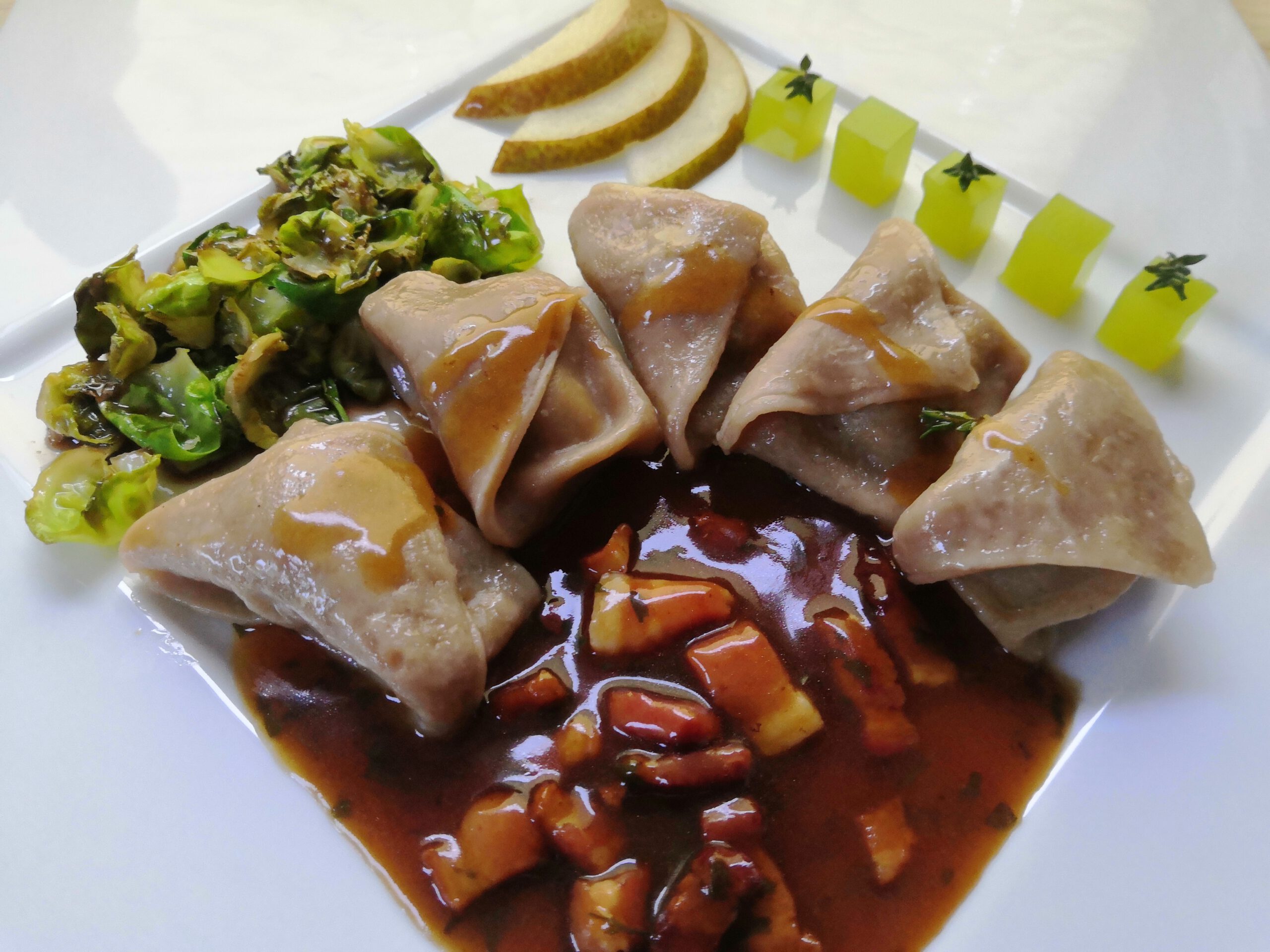 Hausgemachte Steinpilztortellini gefüllt mit Wildschweinfarce auf Sherry-Speck-Kräuterjus, karamellisierte Rosenkohlblätter mit dunklem Balsamico, grünes Birnen-Thymiangelee